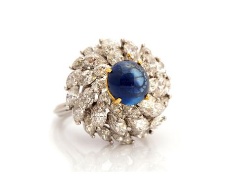 A sapphire and diamond ring, the cabachon cut blue  sapphire weighing approx 3 carats, claw set centrally with a three tiered