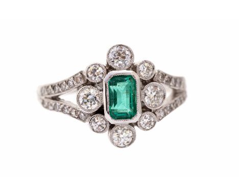 An emerald and diamond 18ct gold ring, the central set emerald approx 0.75ct, with a floral surround of rub-over set brillian