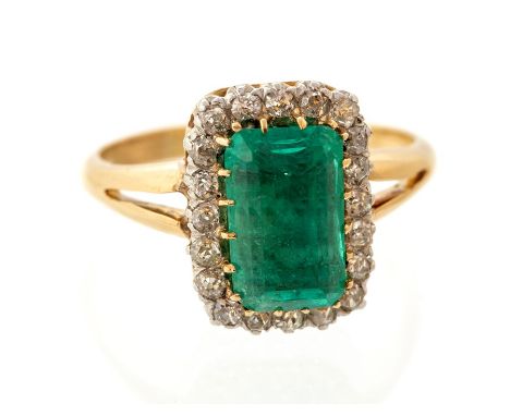 An emerald and diamond  rectangular cluster ring, the central rectangular step cut emerald accompanied by and Anchor cert jew