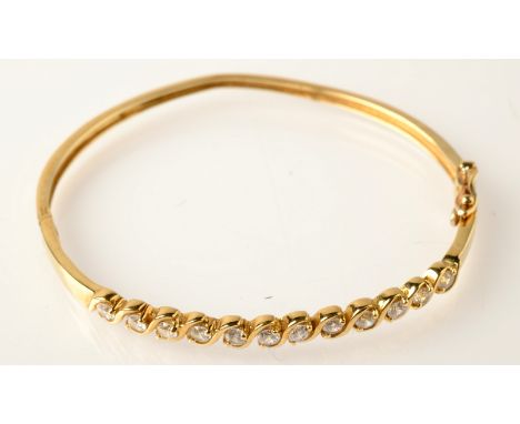 A modern 9ct. gold bangle set with white stones.
