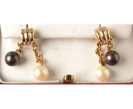 A pair of Cartier two colour gold earrings, each set with a single natural pearl and a single black pearl. Cartier box. 