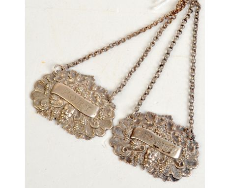A pair of George IV silver decanter labels, each decorated with the head of the God Bacchus against a ground of fruiting vine
