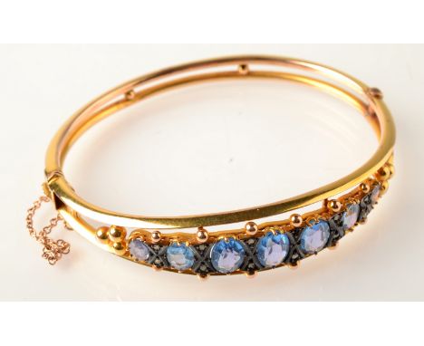 A 9ct. gold Edwardian Chester hallmarked gold bangle set with blue stones and diamond chips.