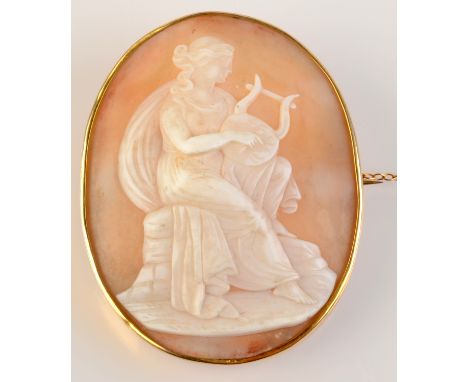 A gold cameo brooch carved with a lady playing a lyre.