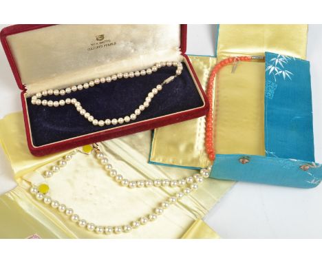 A coral necklace and two simulated pearl necklaces. 