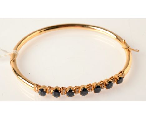 A gold bangle set diamonds and sapphires. 