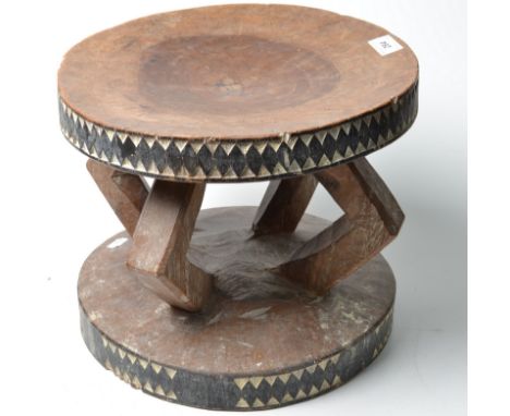 An African stool with shallow geometric carving coloured black and white on four angular supports. 
