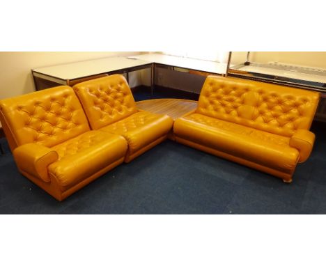 A RETRO MUSTARD BUTTON UPHOLSTERED VINYL CORNER SUITE, comprising two seater settee, two single chairs and a quatrefoil wood 