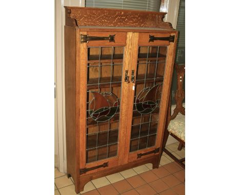 AN OAK ARTS & CRAFTS STYLE DISPLAY CABINET, having leaded stained glass depicting boats in full sail to double doors with fiv