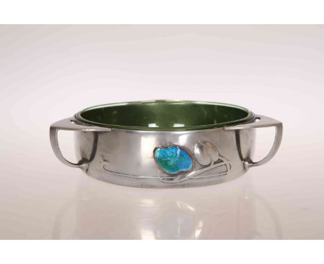 ARCHIBALD KNOX FOR LIBERTY & CO, A TUDRIC PEWTER, ENAMEL AND GREEN GLASS BOWL, circular with three lug handles, cast in low r