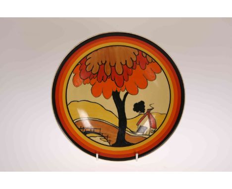 "HOUSE AND BRIDGE", A CLARICE CLIFF PLATE, c. 1931, circular, painted with a red-roofed cottage, a bridge, and a tree with pe