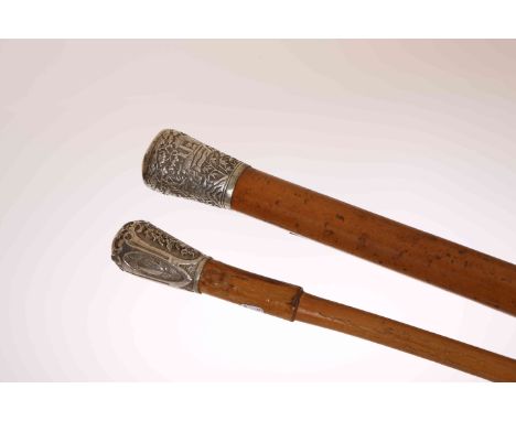TWO WALKING STICKS WITH CHINESE WHITE METAL HANDLES, the first decorated with figures, buildings and trees to the handle, 94.
