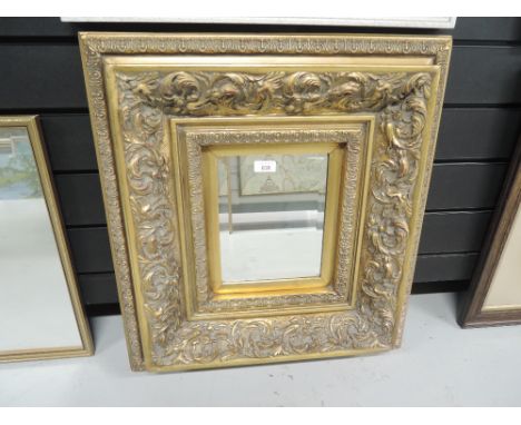 A vintage hall way mirror with elaborate gilt and plaster effect frame and bevel edged glass