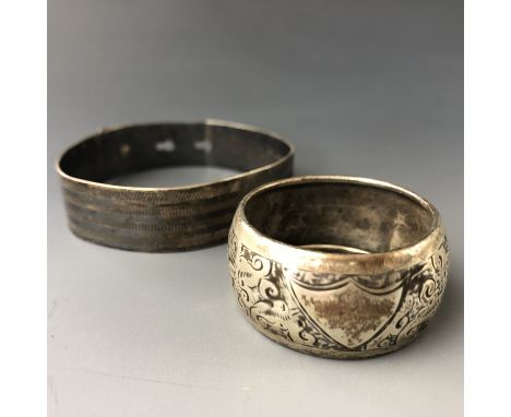 A white metal (tests as silver) bangle with engine-turned decoration, and a silver napkin ring, 33g