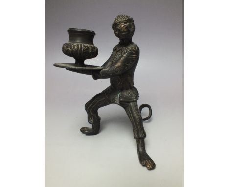 A CAST METAL BRONZED FIGURAL CANDLESTICK, modelled in the form of a dressed monkey holding a tray, the sconce fitted upon the
