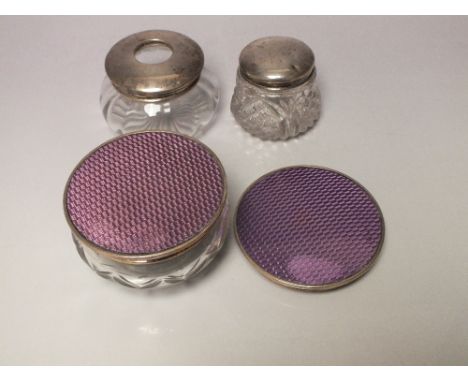 THREE HALLMARKED SILVER TOPPED DRESSING TABLE JARS, one being a purple guilloche enamel example - Birmingham 1929, together w