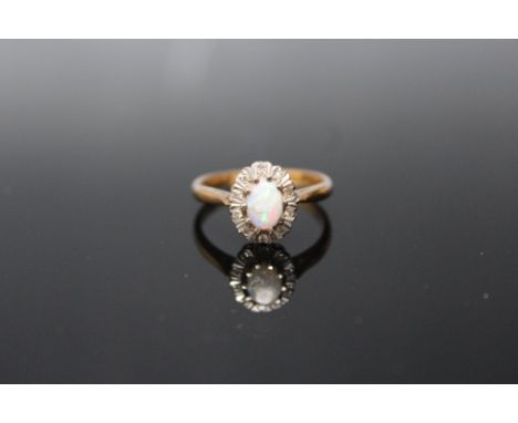 AN 18 CARAT GOLD OPAL AND DIAMOND RING, set with ten brilliant cut diamonds totalling approx 0.10 carat with the central oval