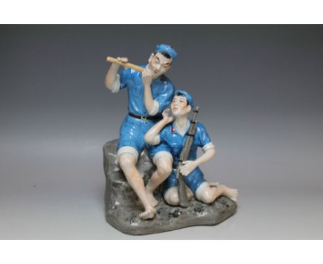 A CERAMIC FIGURE OF TWO CHINESE SOLDIERS, both dressed in blue uniforms with a red star upon their caps, one is holding a rif