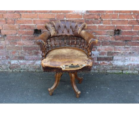 A LATE 19TH CENTURY OAK AND LEATHER SWIVEL ARMCHAIR, button backed with studded detail, raised on four scrolled supports - in