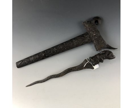 A Malayan kris / dagger, having carved hardwood grip and scabbard, and serpentine blade with characteristic pamor, 51 cm over