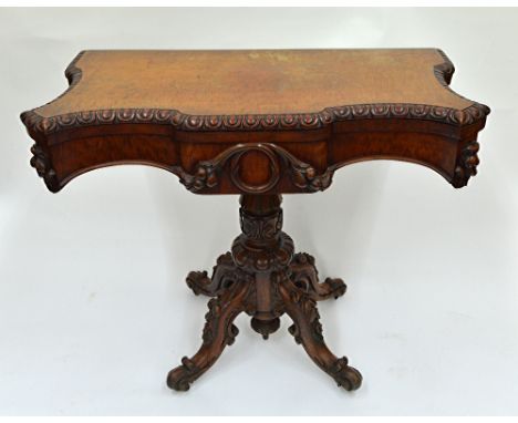 An early Victorian mahogany card table, the hinged fold-over of shaped outline with egg and tongue border, the frieze carved 