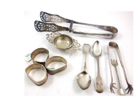 A silver tea strainer, Birmingham 1934, with pierced side handles, 11cm across, two silver fiddle pattern teaspoons, three en