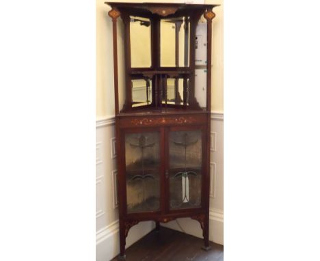 An English Art Nouveau inlaid mahogany corner cabinet, the upper section with mirrored back and shelf on turned spindle suppo