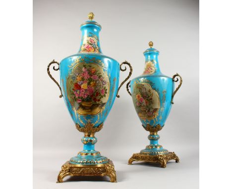 A PAIR OF BLUE SEVRES DESIGN TWO-HANDLED URN SHAPED VASES AND COVERS, light blue ground with reverse panels of flowers, with 