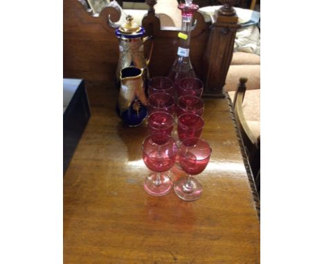 A cranberry glass decanter with eight cranberry drinking glasses; and two Venetian style overlaid glass jugs 
