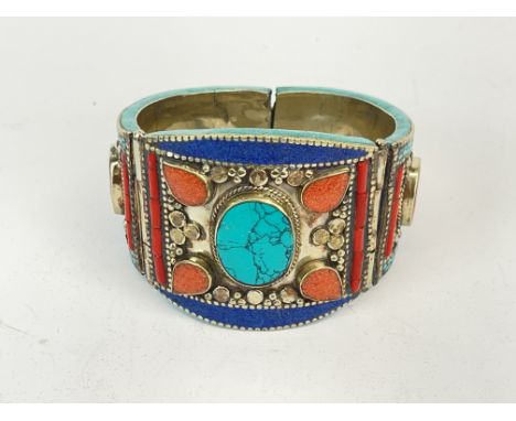 An impressive stone set Tibetan white metal tribal bangle, W. 5.5cm.