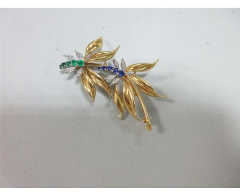 An 18ct gold diamond, emerald and sapphire brooch, designed as an arch of two flowers, with a graduated curve of round cut em