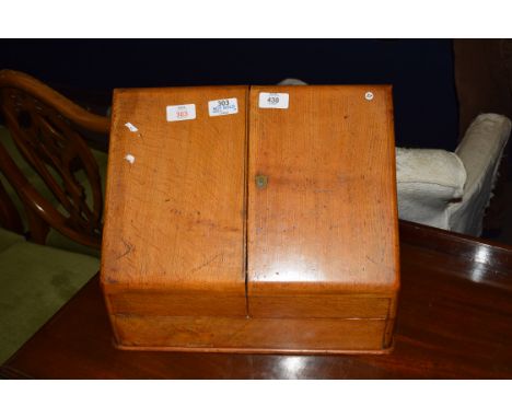 Early 20th century light oak wedge formed stationery cabinet with hinged double doors opening to a fitted interior, 58cm wide