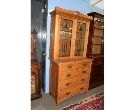 Late 19th century light oak two-piece cabinet, the top section with double glazed doors with Art Nouveau style leaded glass o