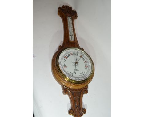 W Norris, Saxmundham, a late 19th century oak cased aneroid barometer and thermometer combination set in a foliate carved oak