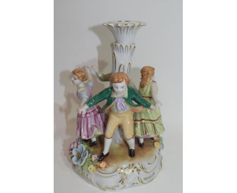 Continental porcelain candlestick in Meissen style decorated with children dancing around a central column, 26cm high