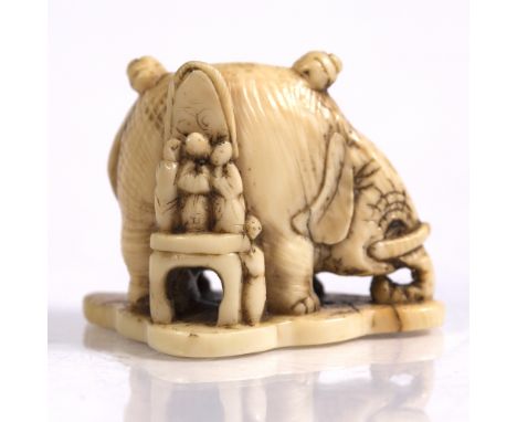 A Japanese ivory netsuke of an elephant Meiji upon which two figures sit and to one side others stand upon a table to clean h