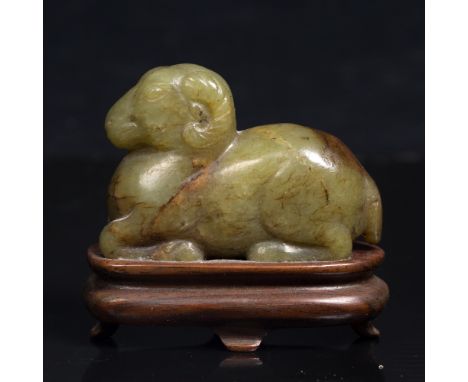 A Chinese green and brown jade reclining ram Ming Dynasty on a wood stand, 4cm x 5cm From a private Oxfordshire collection.