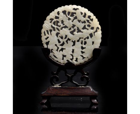 A Chinese white jade pierced and carved medallion decorated with youths as dragon dancers amidst various symbolic objects, on