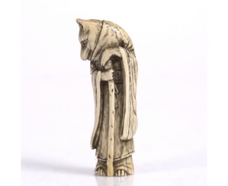 A Japanese ivory netsuke of a standing Fox Priest late Meiji wearing a robe, scarf and holding a staff, 7cm