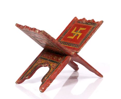 An Indian polychrome painted manuscript stand 19th Century decorated with central swastika and carved details, 23cm across