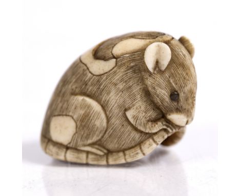 A Japanese ivory netsuke of a pie-bald rat 19th Century squatting holding its tail, inlaid eyes