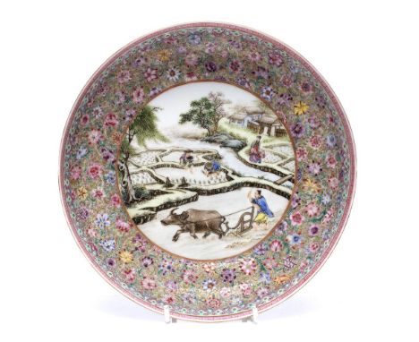 A Chinese saucer dish Republican period decorated in famille rose enamels with a central medallion shaped panels showing a ri