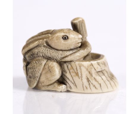 A Japanese ivory netsuke of a squatting rat early 20th Century pounding elixir of life in an hibachi style tub, signed