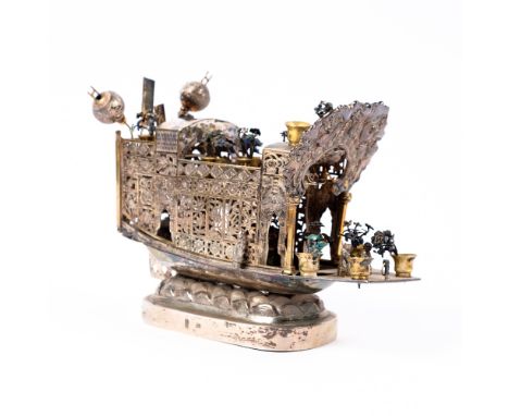 A Chinese white metal model junk late 19th Century with various figures and vases of enamel flowers and lanterns, Chinese cha
