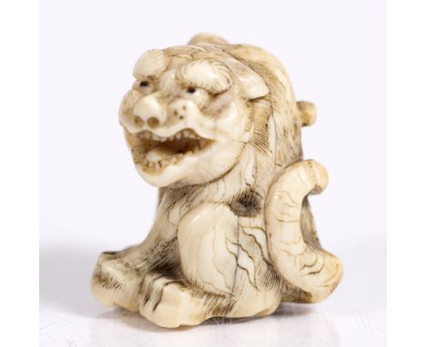 A Japanese ivory netsuke of a seated tiger Meiji period 4cm high