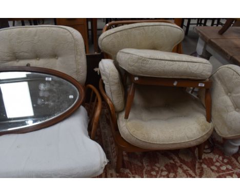 An Ercol stick back three piece lounge suite, comprising two seater settee, armchair and foot stool, each with padded cushion