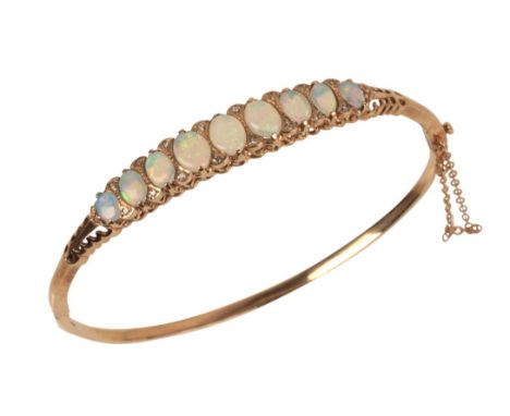 A 9CT GOLD OPAL AND DIAMOND SET BANGLEthe nine iridescent opals graduating from the centre stone measuring approx. 7.22mm x 5