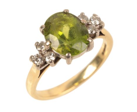 AN 18CT GOLD PERIDOT AND DIAMOND RINGset with an oval cut peridot measuring approx. 9.95mm x 7.87mm, c.2.50 carats, flanked b