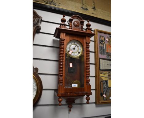 A wooden cased chiming wall clock having carved details and finials to top.