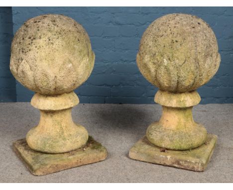 A pair of garden spheres in jagged surround, mounted on baluster columns raised on square plinths. Height: 70cm, Width of pli